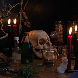a wooden table topped with candles and a skull